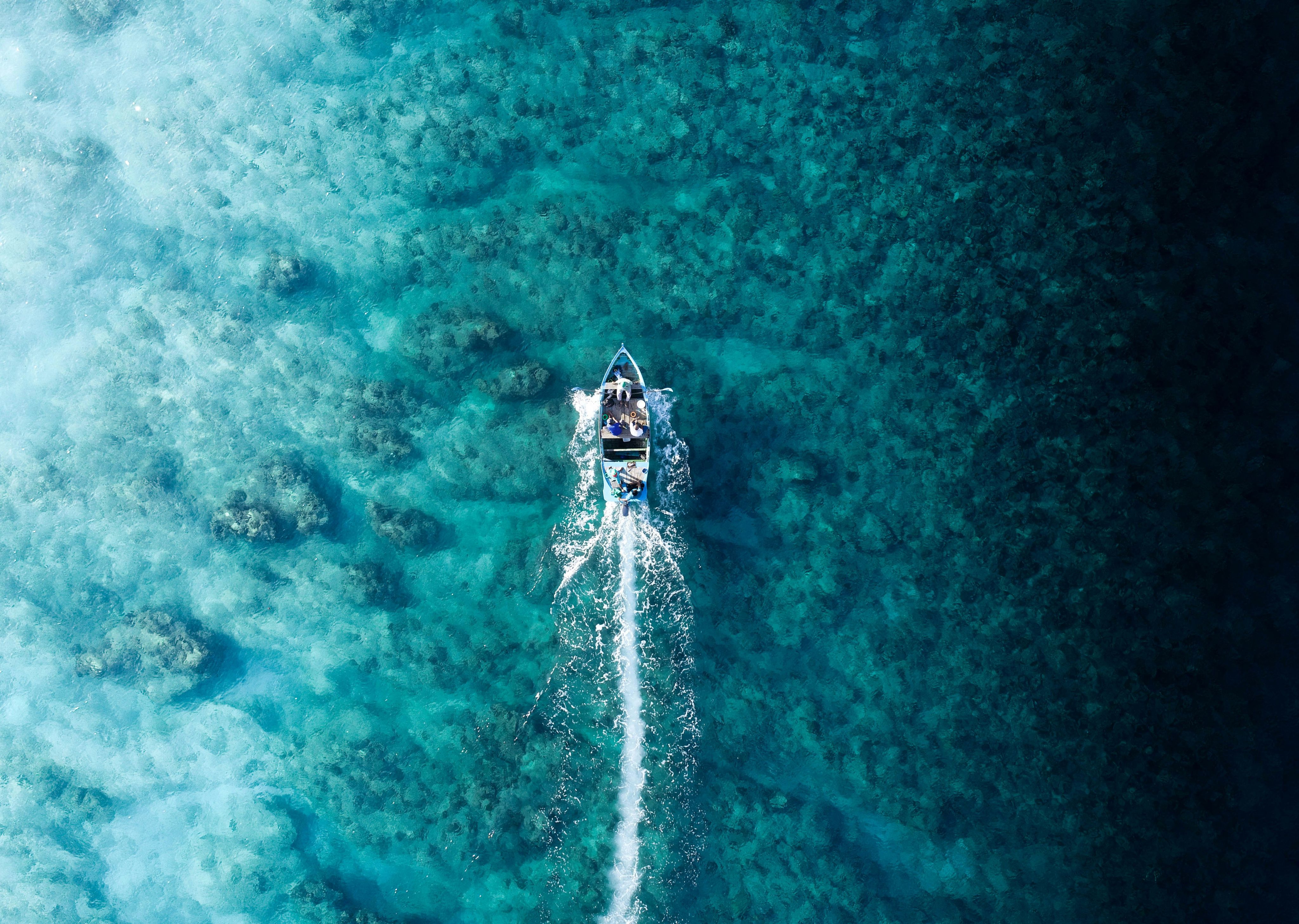 Aerial photo of a small motorboat traveling over clear turquoise water